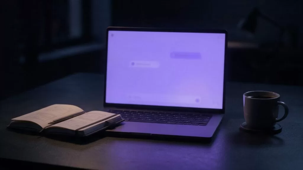 Laptop con una conversación abstracta con un asistente de inteligencia artificial sobre un escritorio de noche